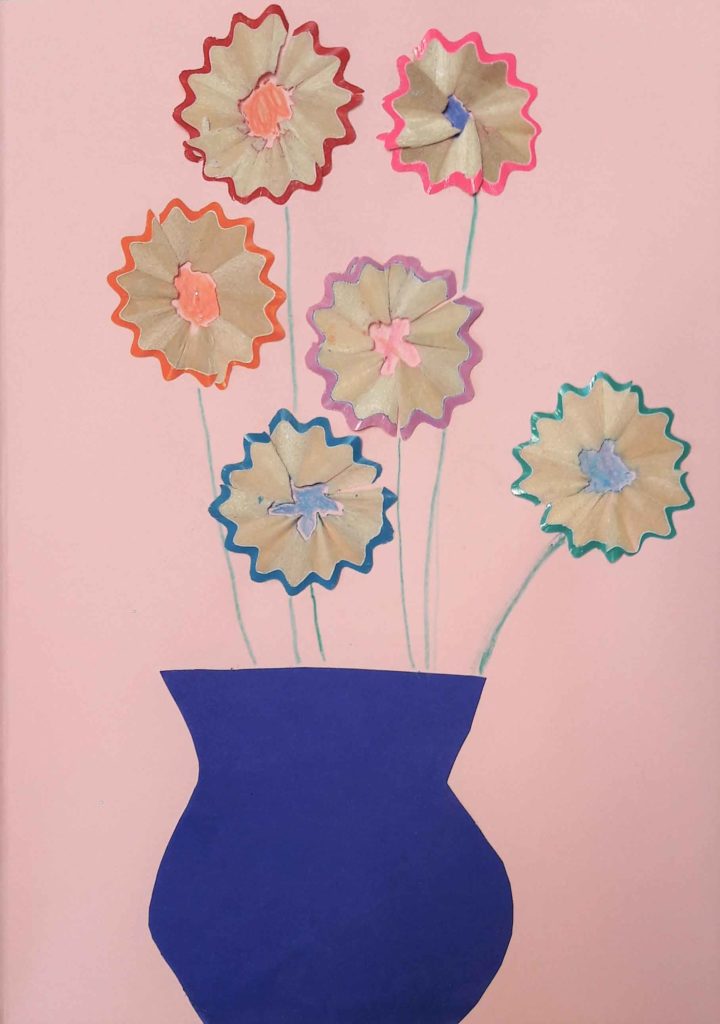 niebieski wazon z papieru z kwiatami zrobionymi z kredek na różowej kartce papieru