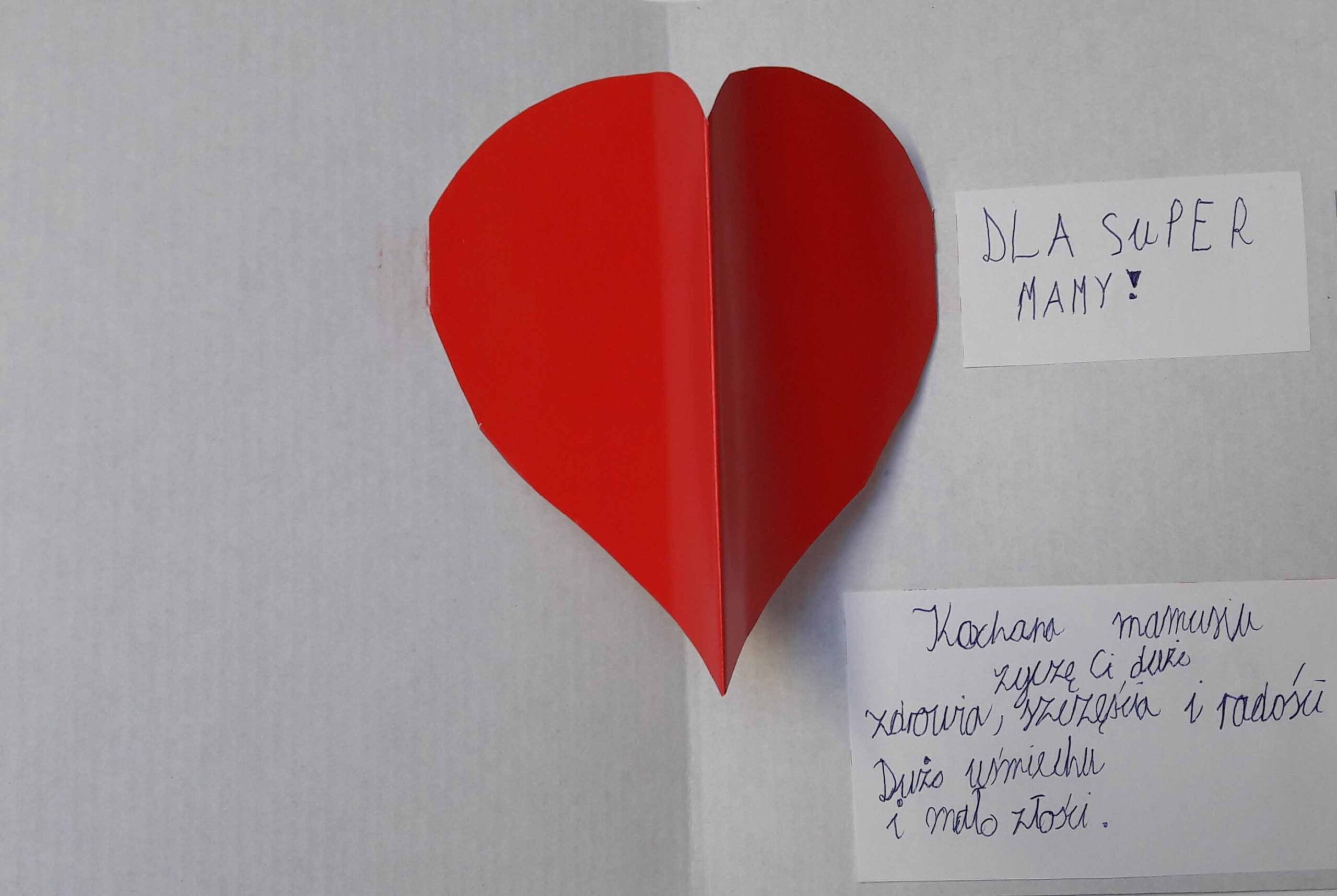 czerwone serce w środku białej kartki papieru z życzeniami na dzień mamy
