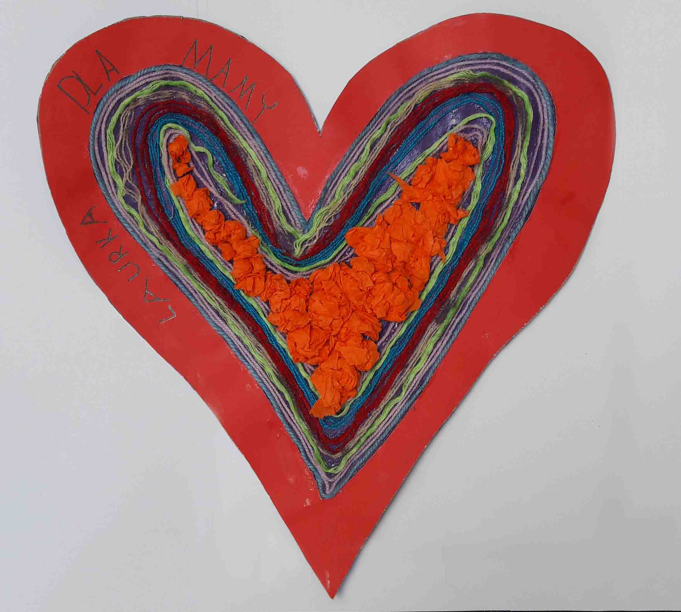 serce z czerwonej kartki w środku którego w kształt serca ułożone są kolorowe sznurki i bibuła