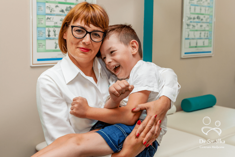 dr n med. Katarzyna Smółka trzyma na rękach dziecko z porażeniem mózgowym