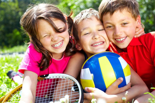 uśmiechnięte dzieci z piłką do siatkówki i paletką do tenisa