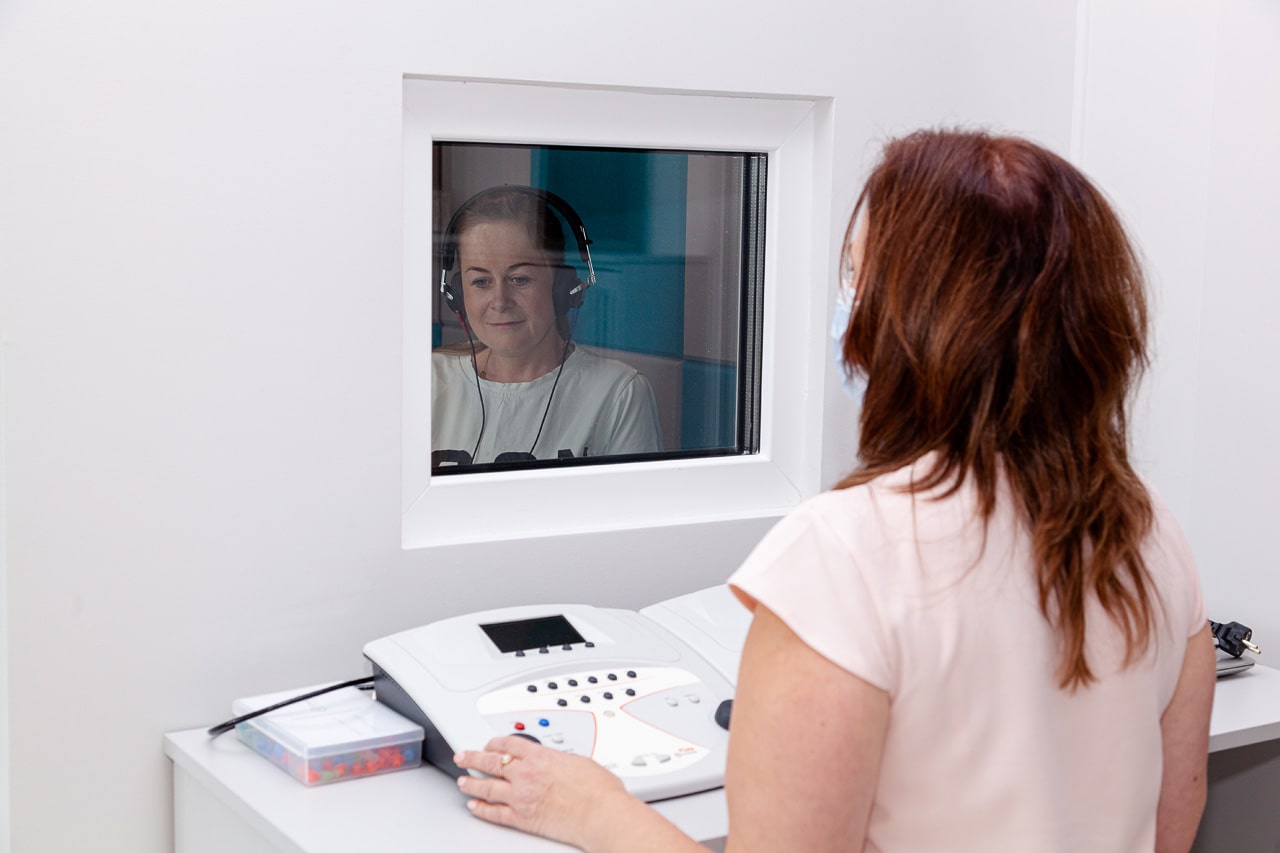kobieta w komorze audiometrycznej podczas badania słuchu