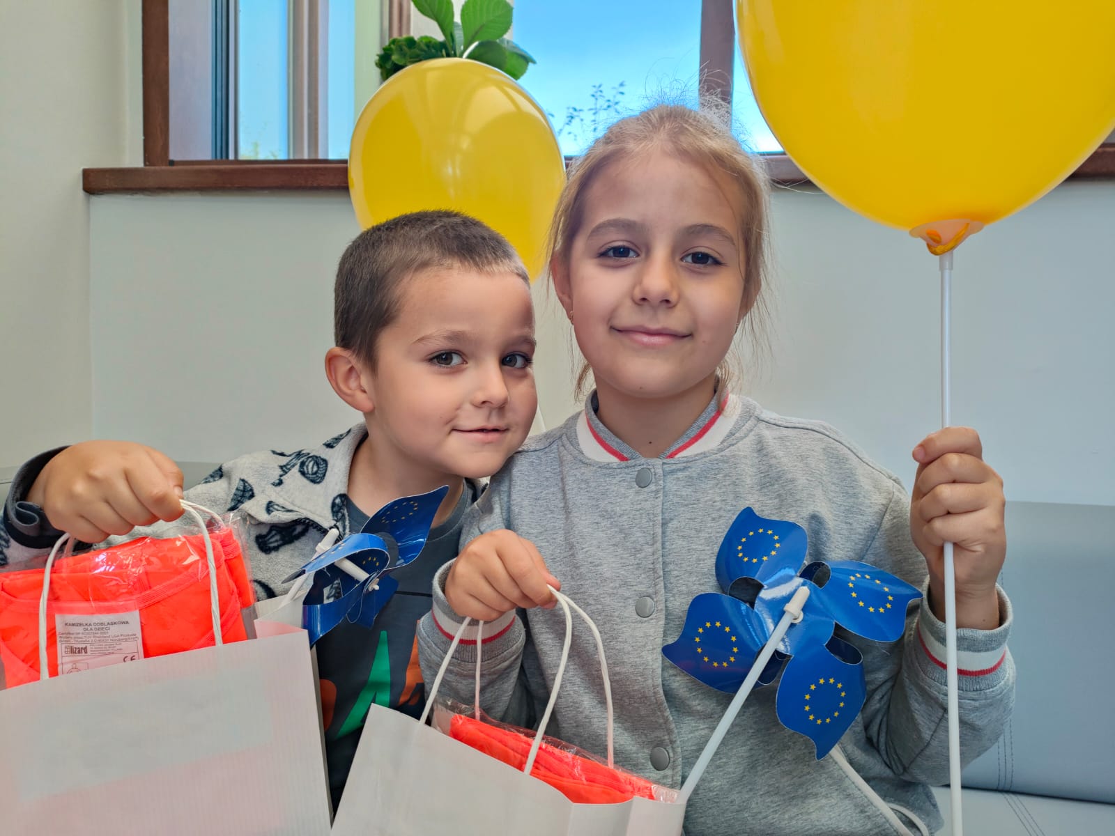 chłopiec i dziewczynka trzymają w rękach torby z prezentami